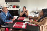 A photo of two people sitting across a table with a community health worker.