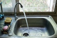 A photo of a kitchen faucet running.