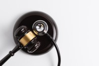 A photo of a gavel and stethoscope resting on a gavel block.