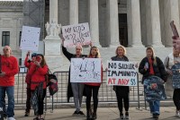 People protest with handmade signs outside the Supreme Court