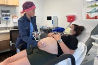 Taylar Swartz uses an ultrasound scanner on a pregnant patient's belly.